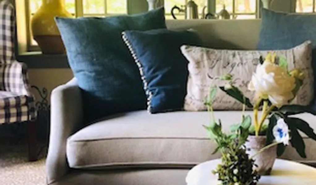 A neutral sofa layered with velvet and patterned pillows